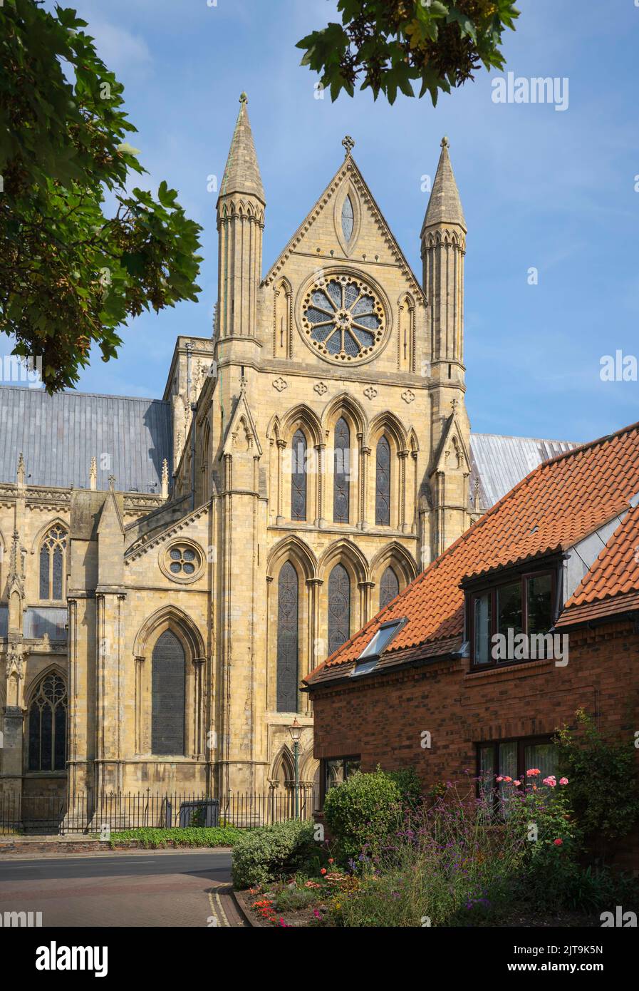 The ancient minster flanked by trees under a blue sky with hazy clouds on a bright summer day in Beverley, Yorkshire, UK. Stock Photo