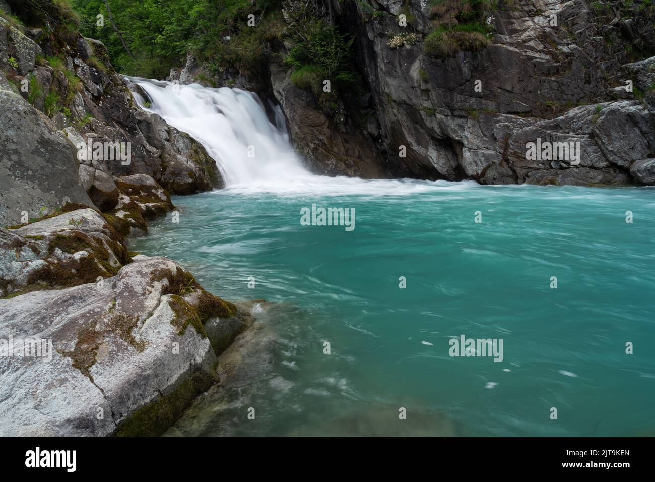 A scenic view of a waterfall flowing down the rocks covered with ...