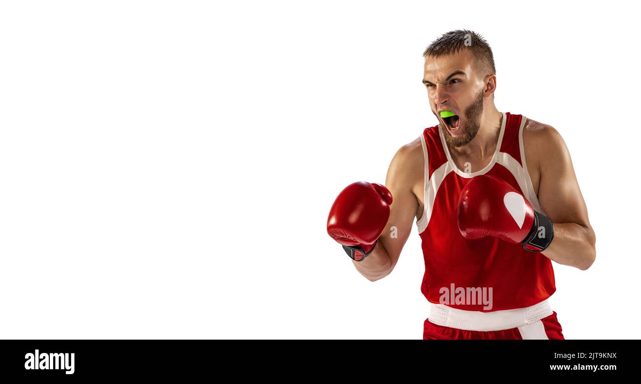 The spirit of victory. Male boxer in red uniform and boxing gloves training isolated on white background. Strength, attack and motion, betting concept Stock Photo