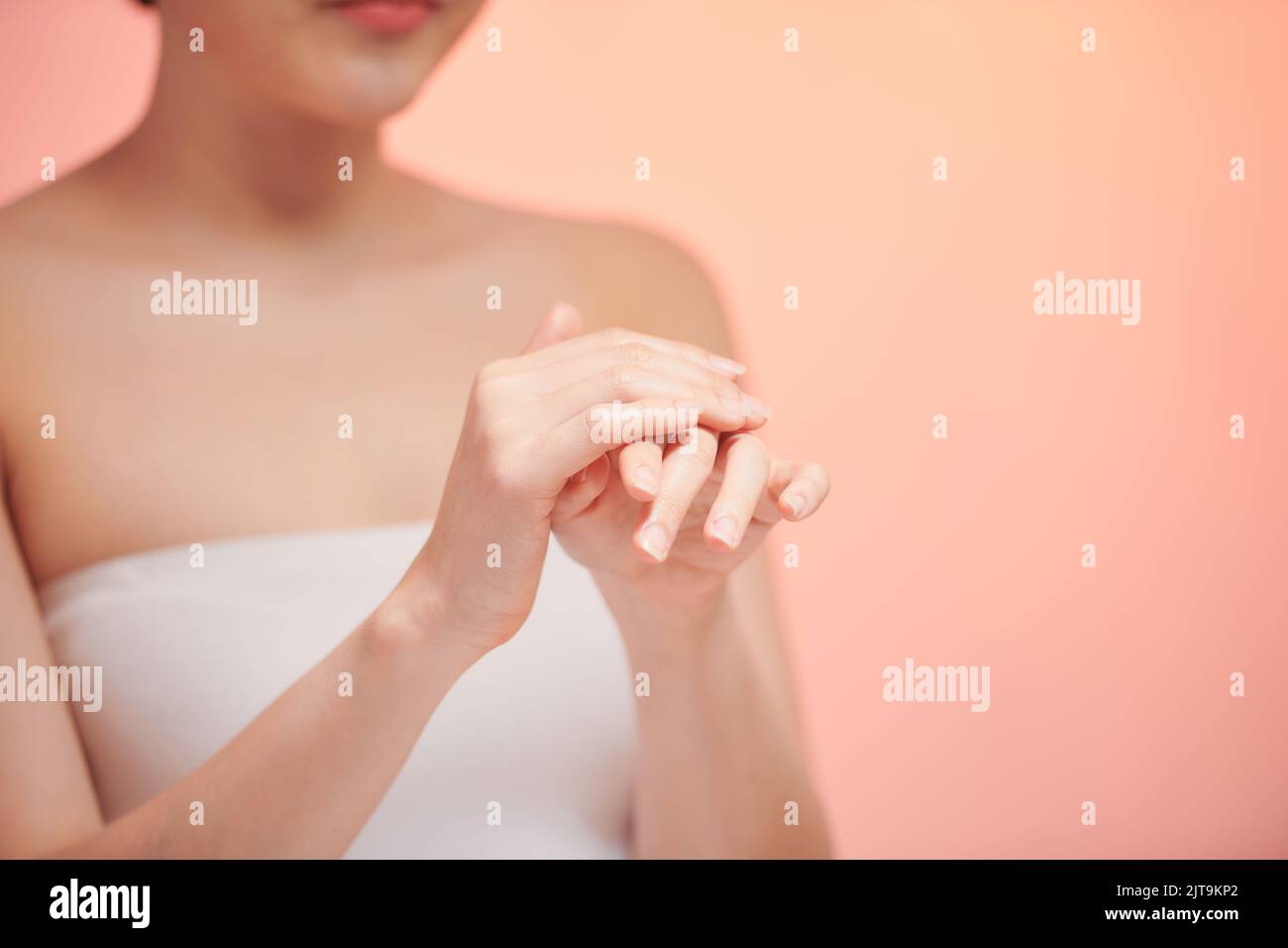 Smiling young woman applies cream on her hands. Stock Photo