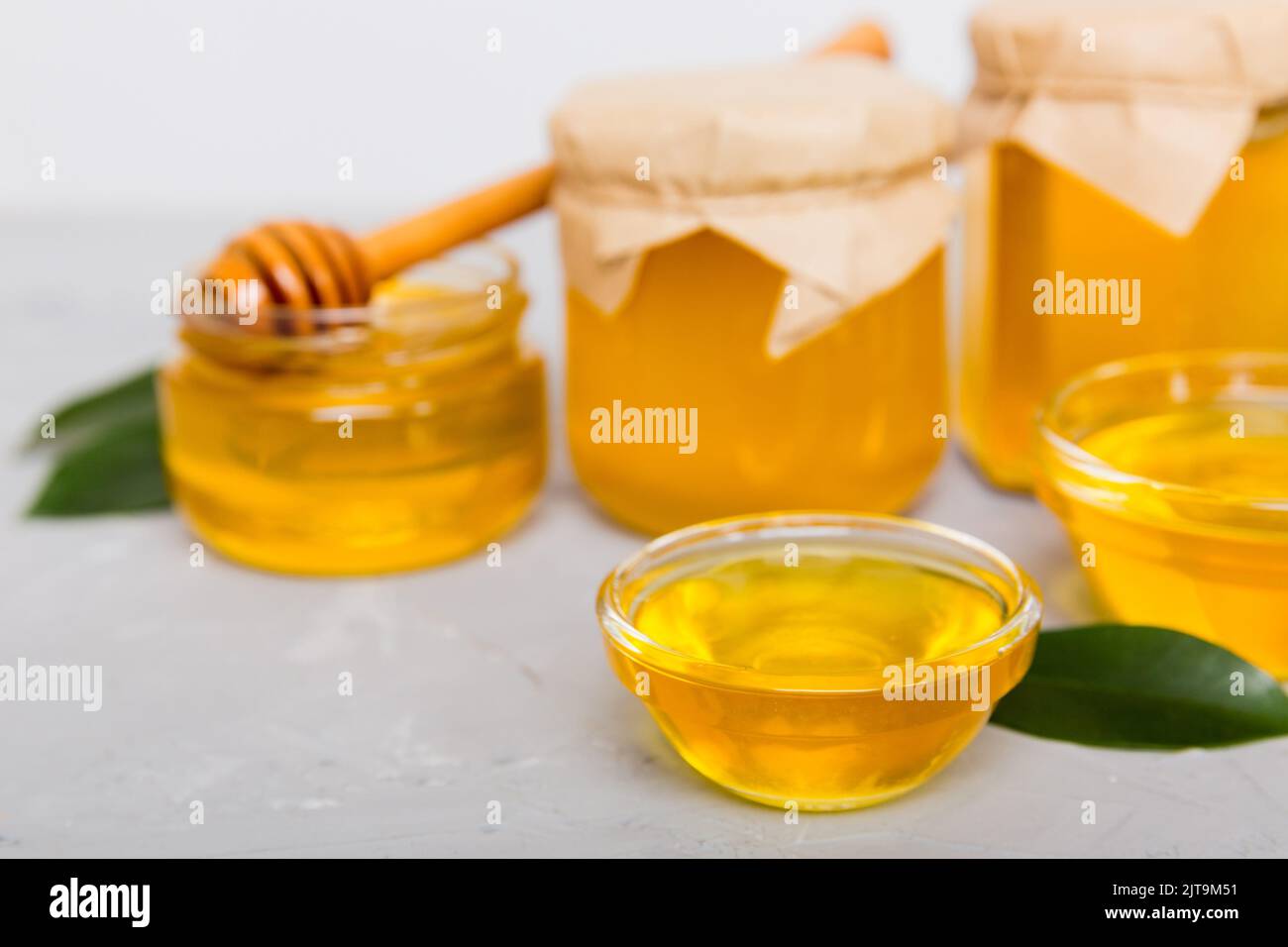 Honey in jar with leaves and honey dipper on colored background top