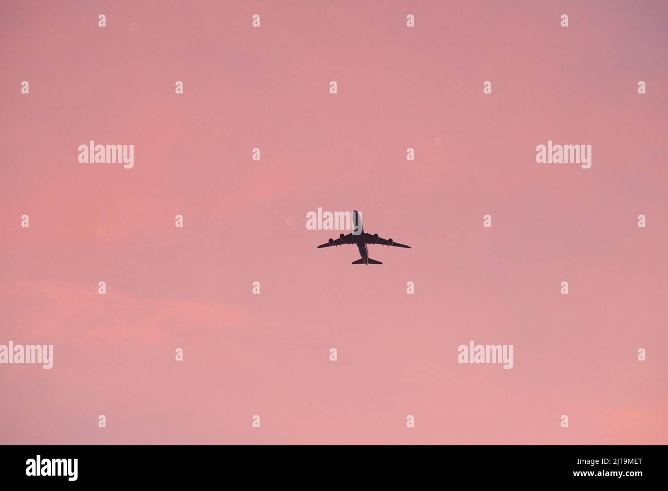 An airplane flying in the pink sunset sky over Hong Kong Stock Photo ...