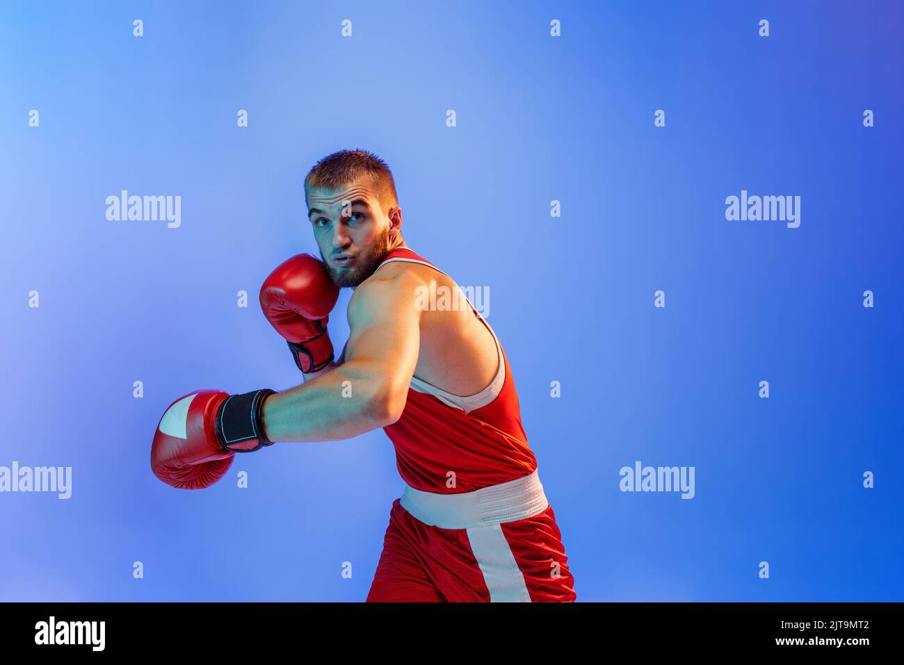 Knockout punch. Male boxer in red uniform and boxing gloves training