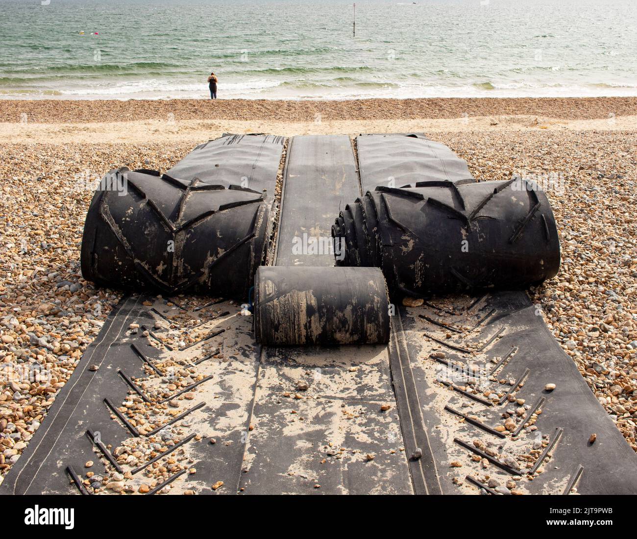 Black rubber mat laid out on Littlehampton beach to allow boats to be rolled out into the sea Stock Photo
