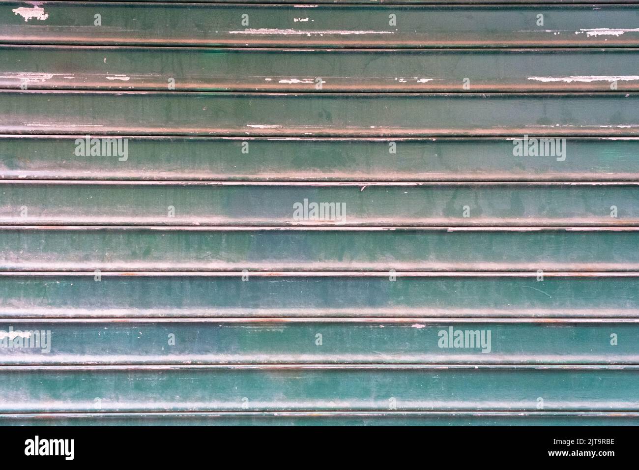 Dirty textured steel garage door painted in green, background, striped metal colored shutter wall, abstract horizontal lines, grunge texture and patte Stock Photo