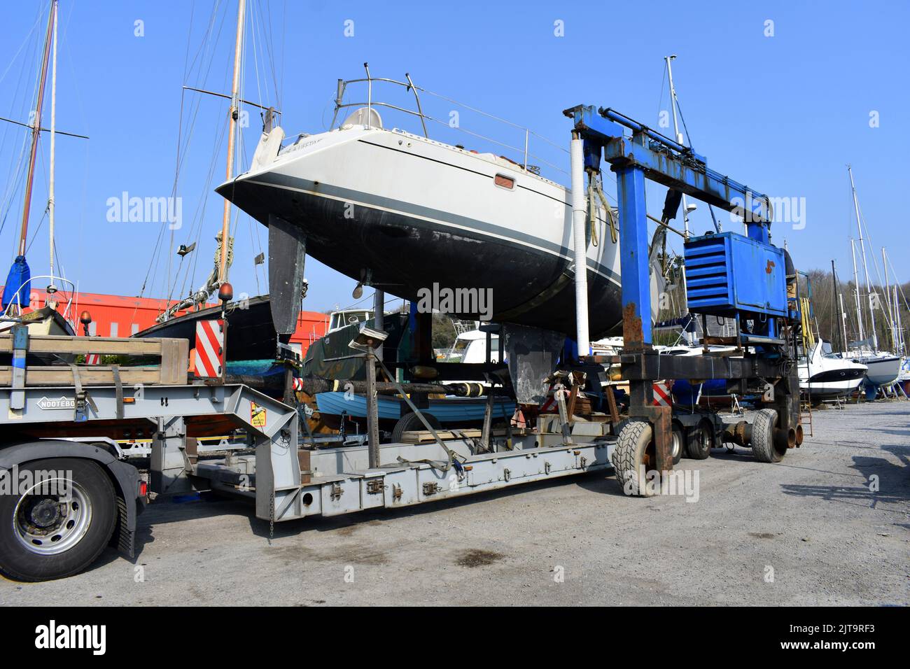Sailing boat being lifted off a truck into East Llanion boatyard, East Llanion, Pembrokeshire, Wales Stock Photo
