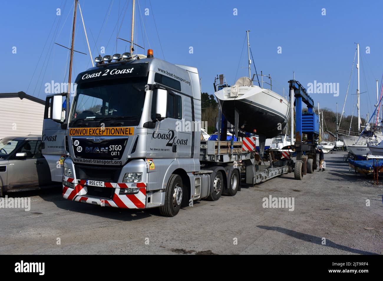Sailing boat being transported on a truck into East Llanion boatyard, East Llanion, Pembrokeshire, Wales Stock Photo
