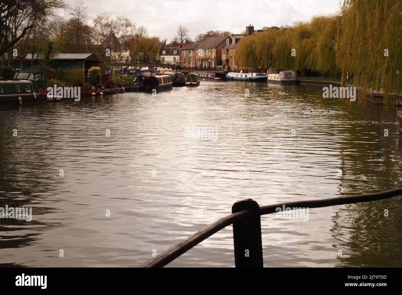 A view of the canal basin at Ely, Cambridgeshire, England, with moored barges, waterside buildings and  weeping willow trees Stock Photo