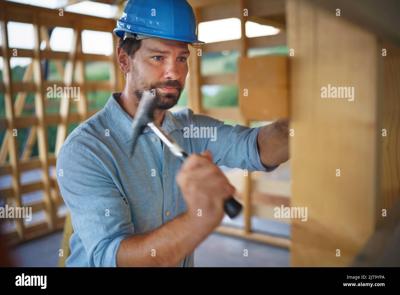 Construction worker working with hammer on wooden frame, diy eco ...
