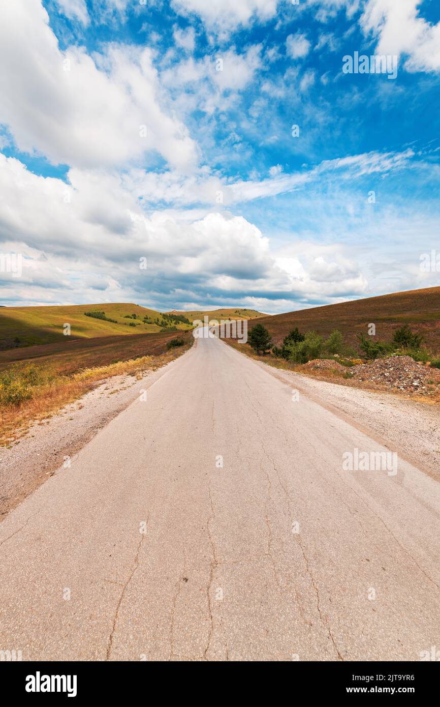 Empty asphalt road through beautiful Zlatibor region landscape stretching in diminishing perspective and disappearing behind the green hill of this fa Stock Photo