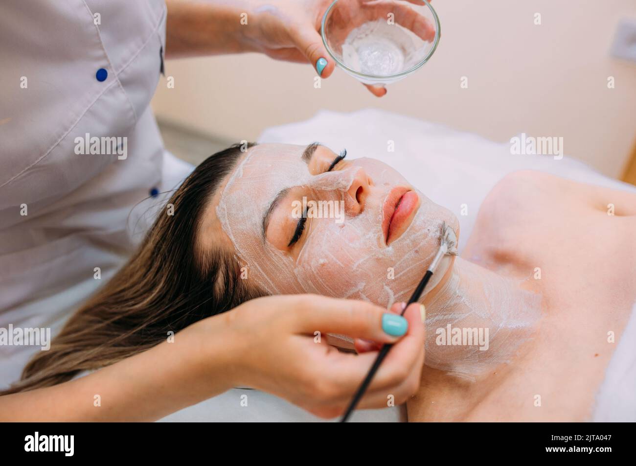 Cosmetologist makes cleansing peeling and face mask for woman. Beauty skin care Stock Photo