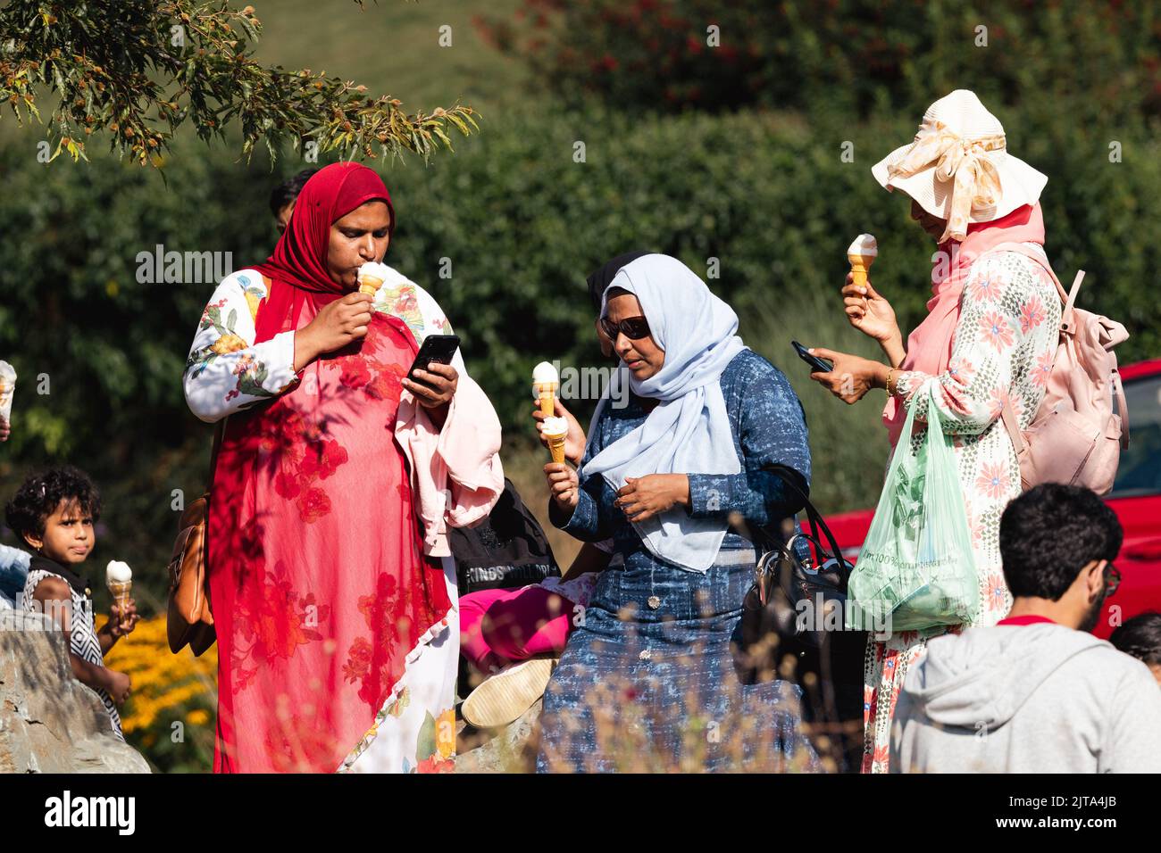 Muslim women in traditional dress om holiday earing ice cream at Lake Windermere Cumbria UK Stock Photo