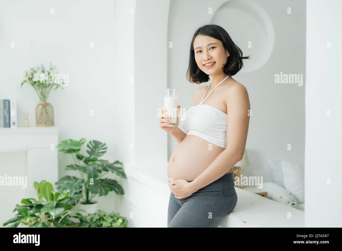 Beautiful pregnant woman drinking milk at home Stock Photo