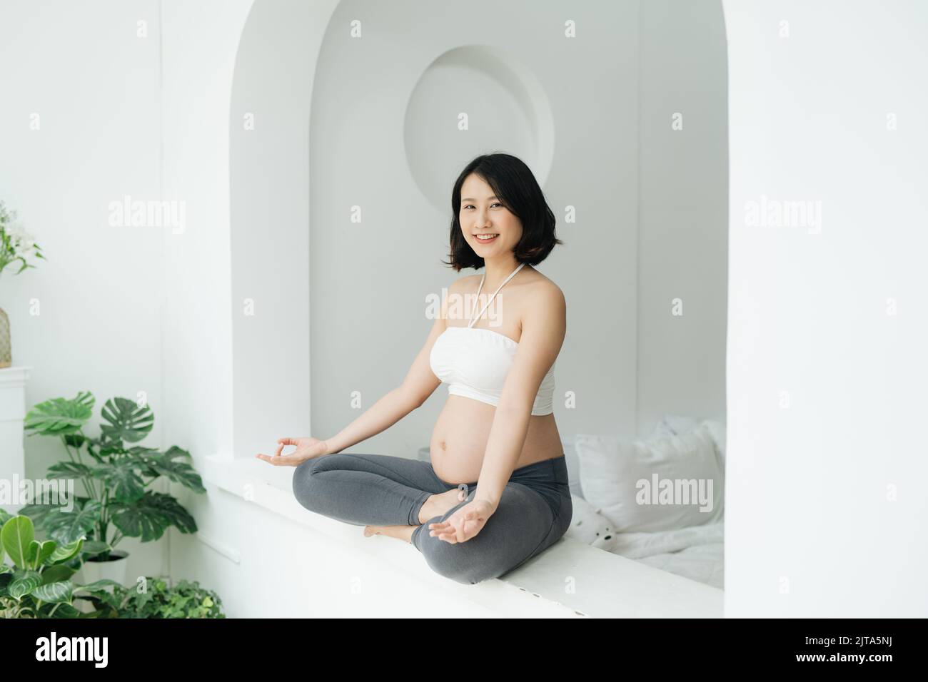 Relaxed pregnant woman practicing yoga at home Stock Photo