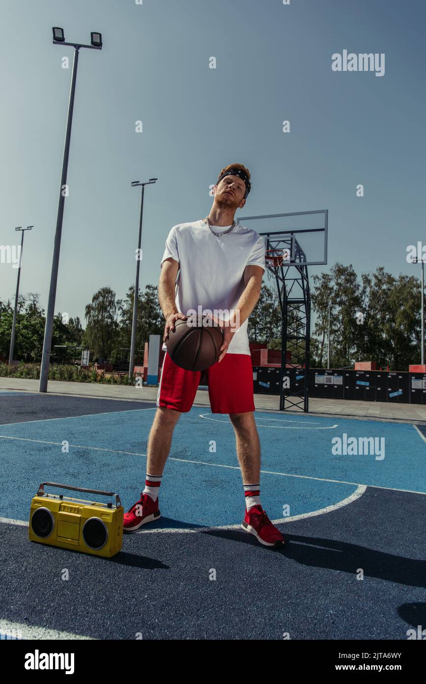 full length of basketball player standing near boombox with ball Stock Photo