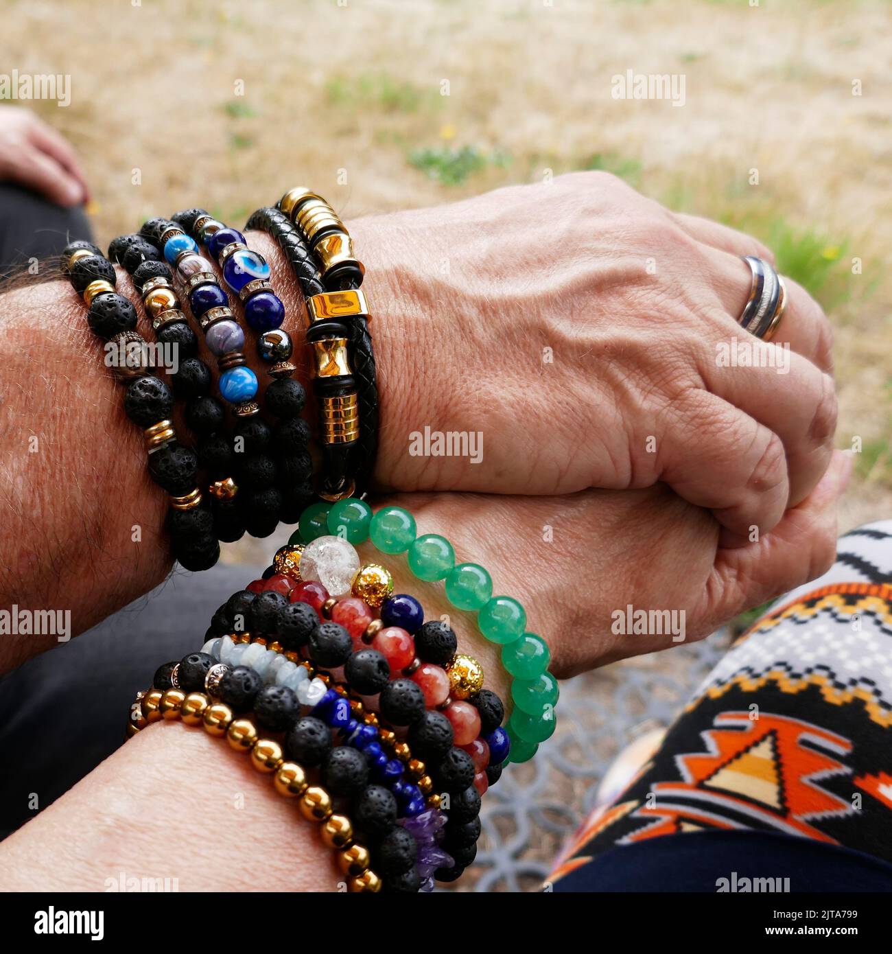 Senior couple holding hands. They are both fond of breaded bracelets. Pair look Stock Photo