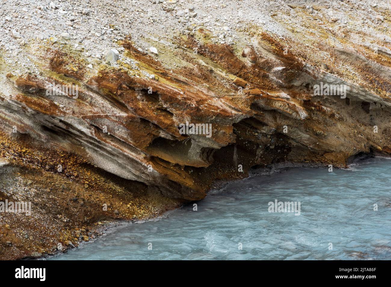 hydrothermal mineralised stream flowing on the slope of the volcano among the banks of volcanic ash and tephra Stock Photo