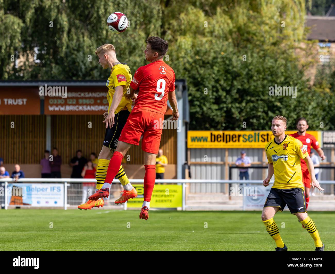 Two players compete for a high ball in a match at Belper Town FC v Warrington Rylands FC Stock Photo