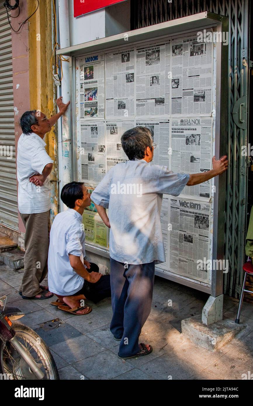 Vietnam, Hanoi Reading newspapers on the wall has been usual from as long as newspapers exist and it still happens these days. Stock Photo