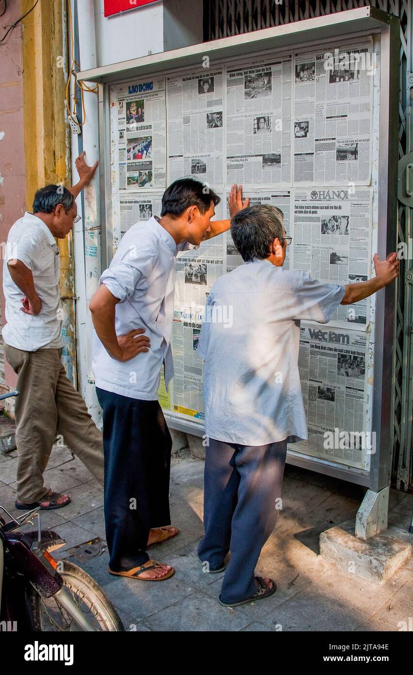 Vietnam, Hanoi Reading newspapers on the wall has been usual from as long as newspapers exist and it still happens these days. Stock Photo