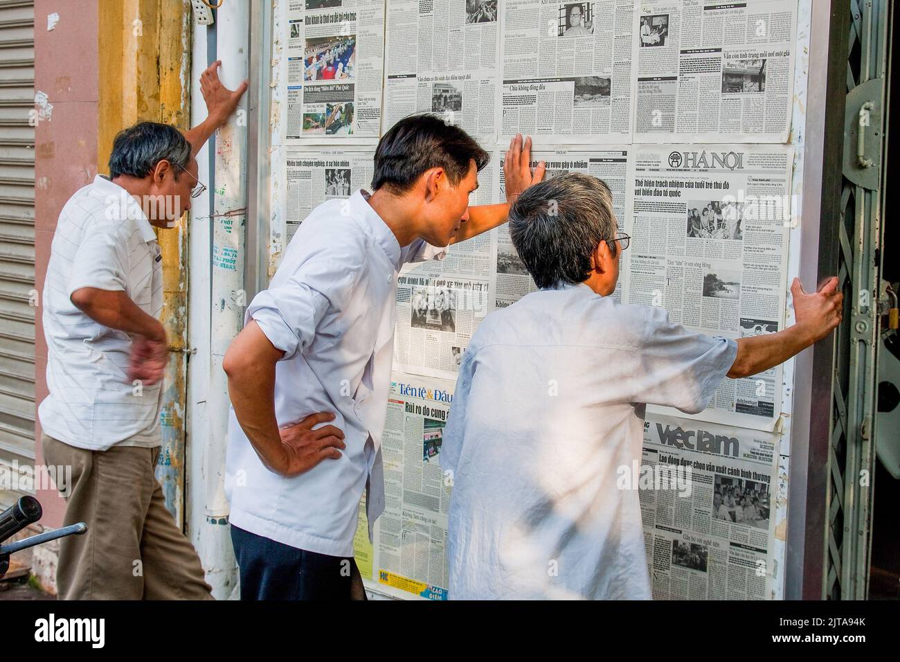 Vietnam, Hanoi Reading newspapers on the wall has been usual from as long as newspapers exist and it still happens these days. Stock Photo