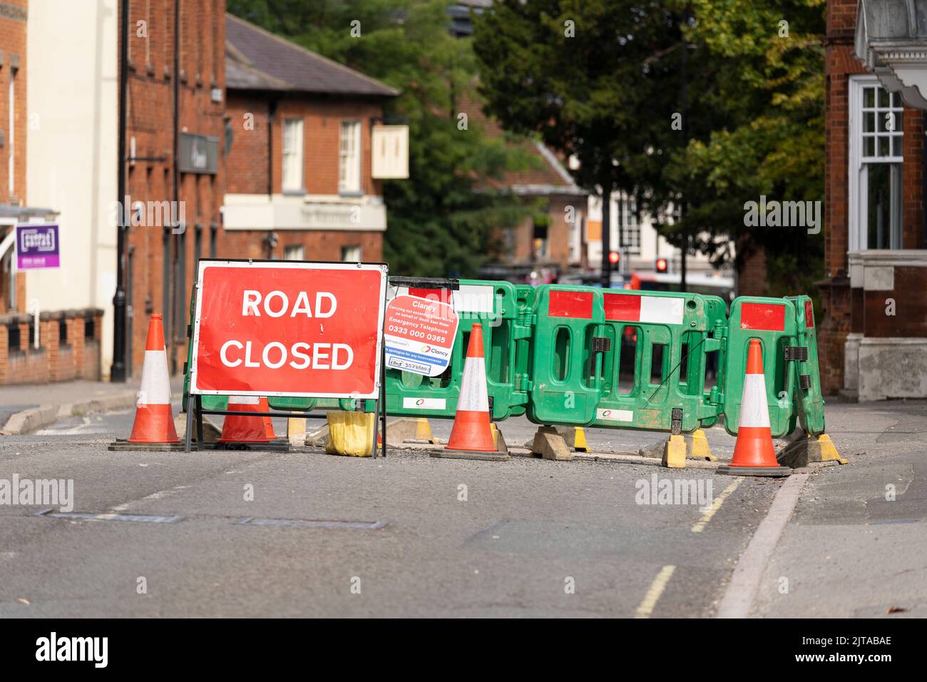 Road closed sign and traffic being diverted around Winchester Road, with road works for repairing a burst water main in the road. Basingstoke, UK Stock Photo