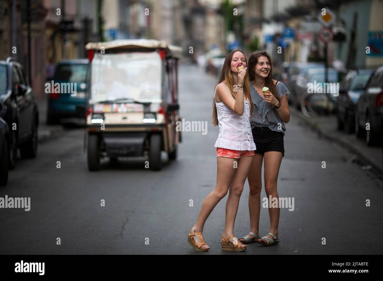 Two pretty girls girlfriends eat m in the middle of the street. Stock Photo