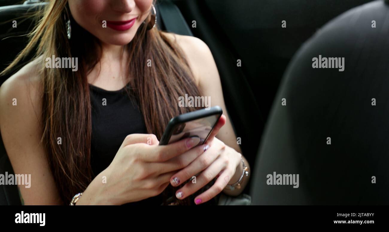 attractive passenger young woman in backseat taxi car using cellphone and smiling to camera 2JTABYY