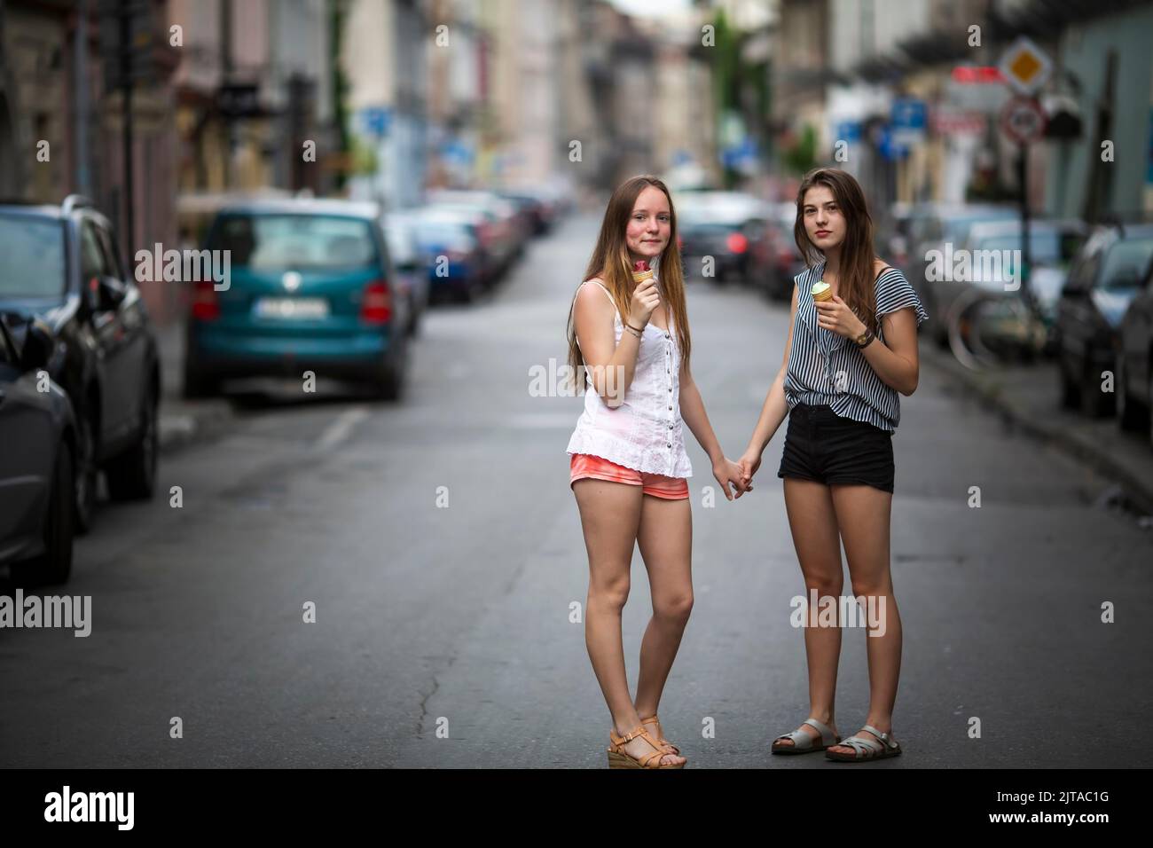 Two teen girls girlfriends eat m in the middle of the street. Stock Photo