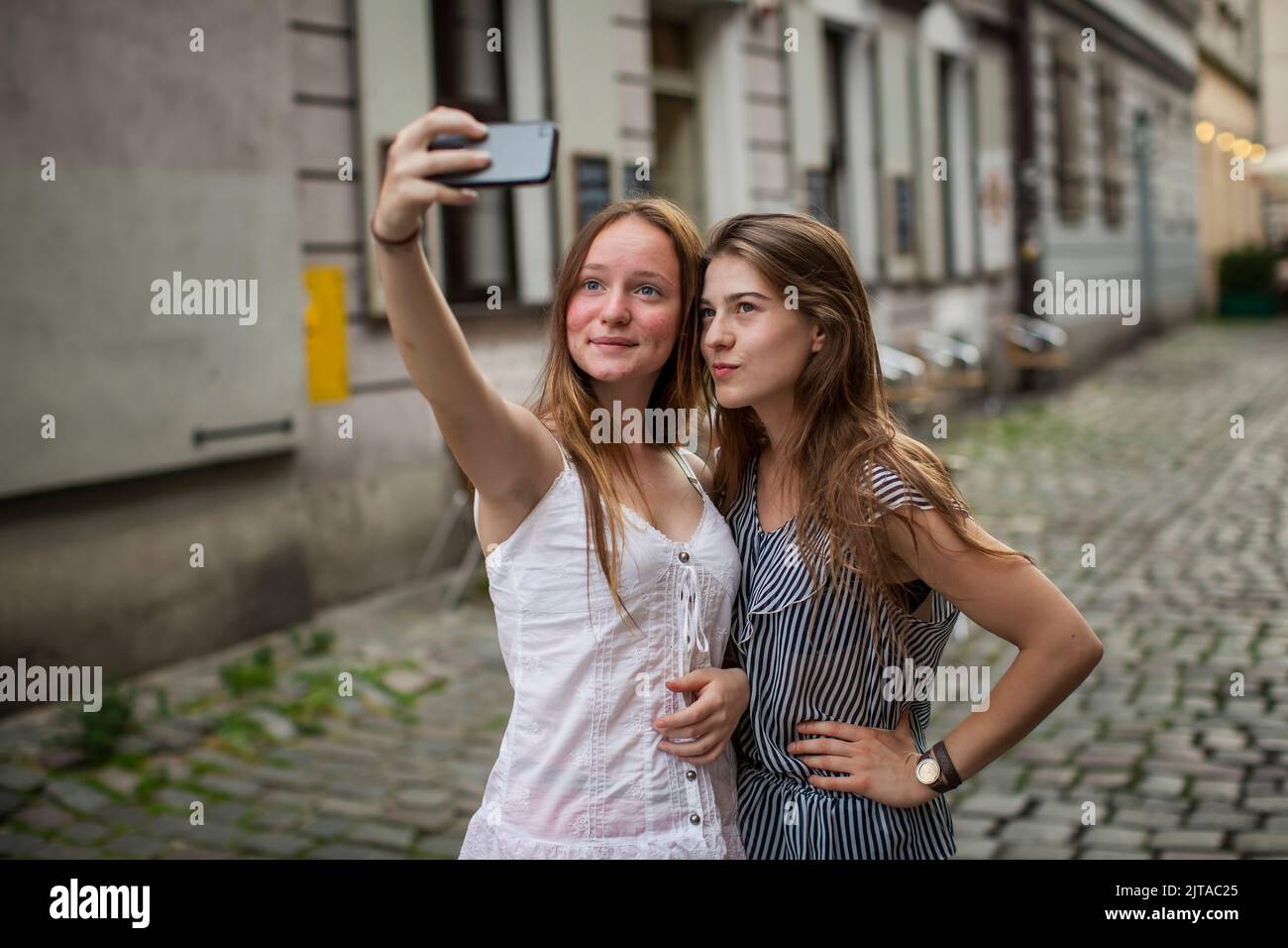 Two pretty girls taking selfies on the street. Stock Photo