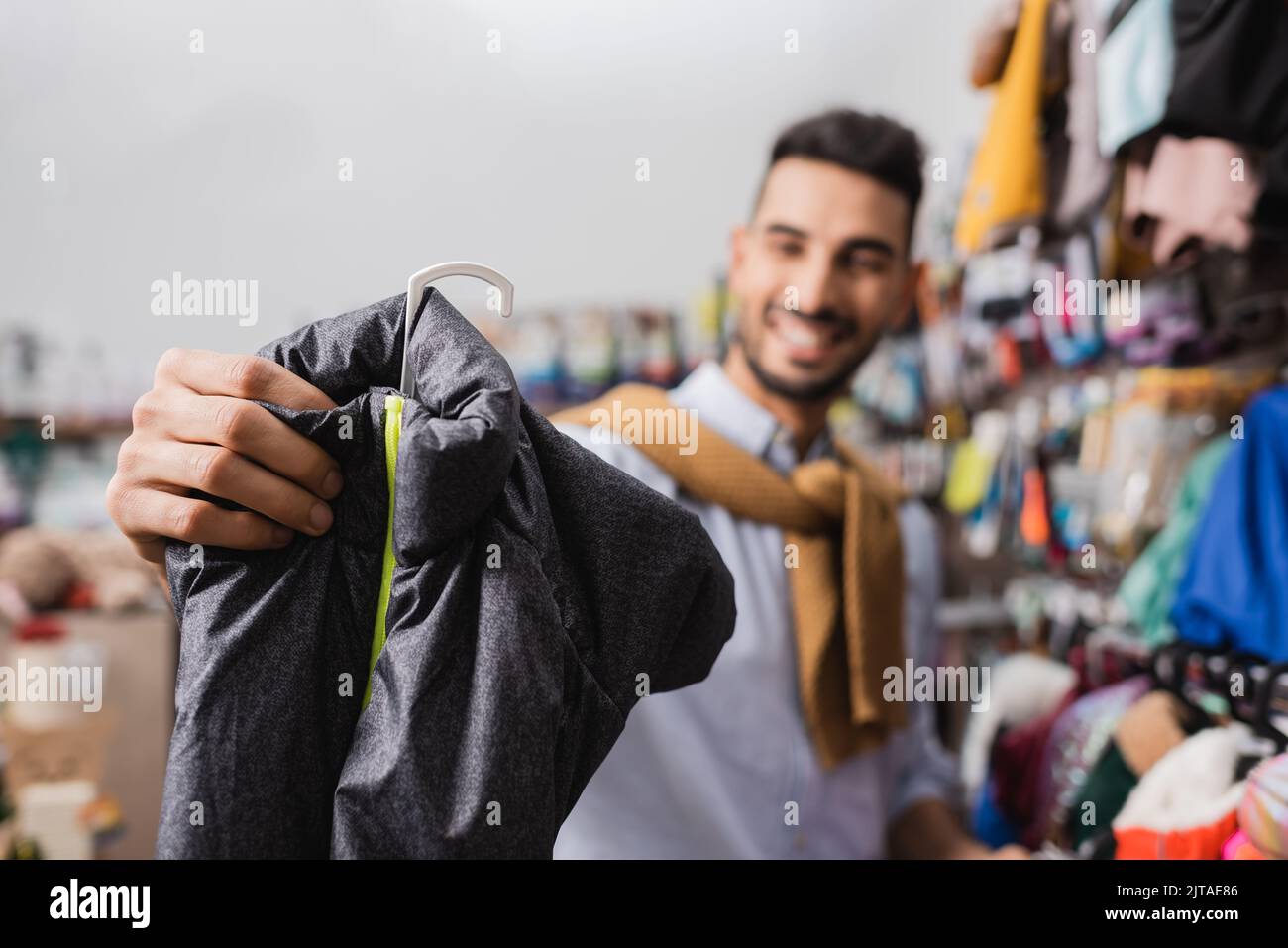 Blurred man choosing animal jacket in pet shop Stock Photo