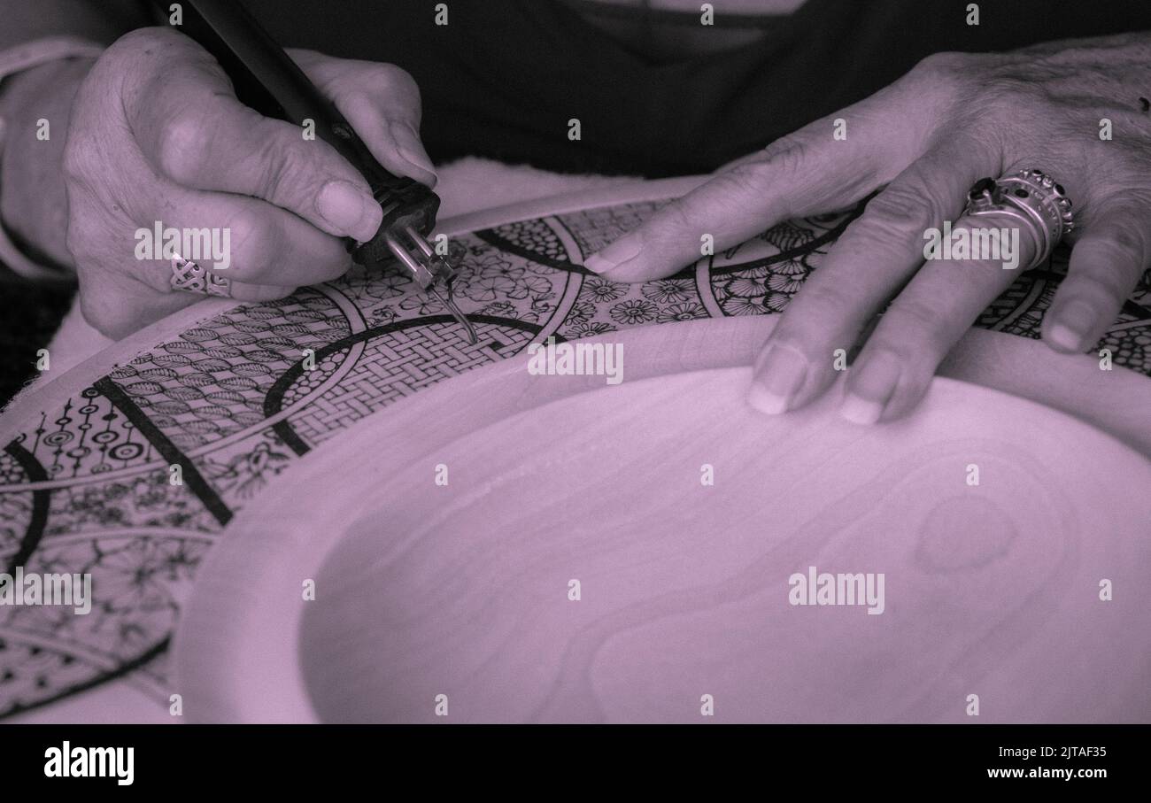 Abstract close-up of an artist handcrafting her artistic designs onto wood using a pyrography burner. Stock Photo