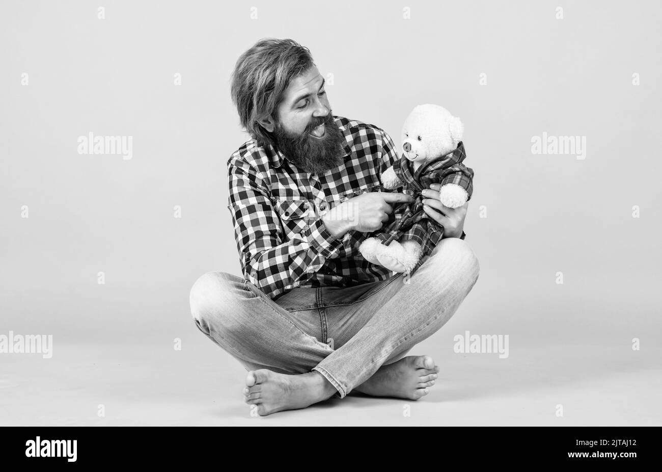 brutal bearded man wear checkered shirt having lush beard and moustache with teddy bear toy, valentines day Stock Photo