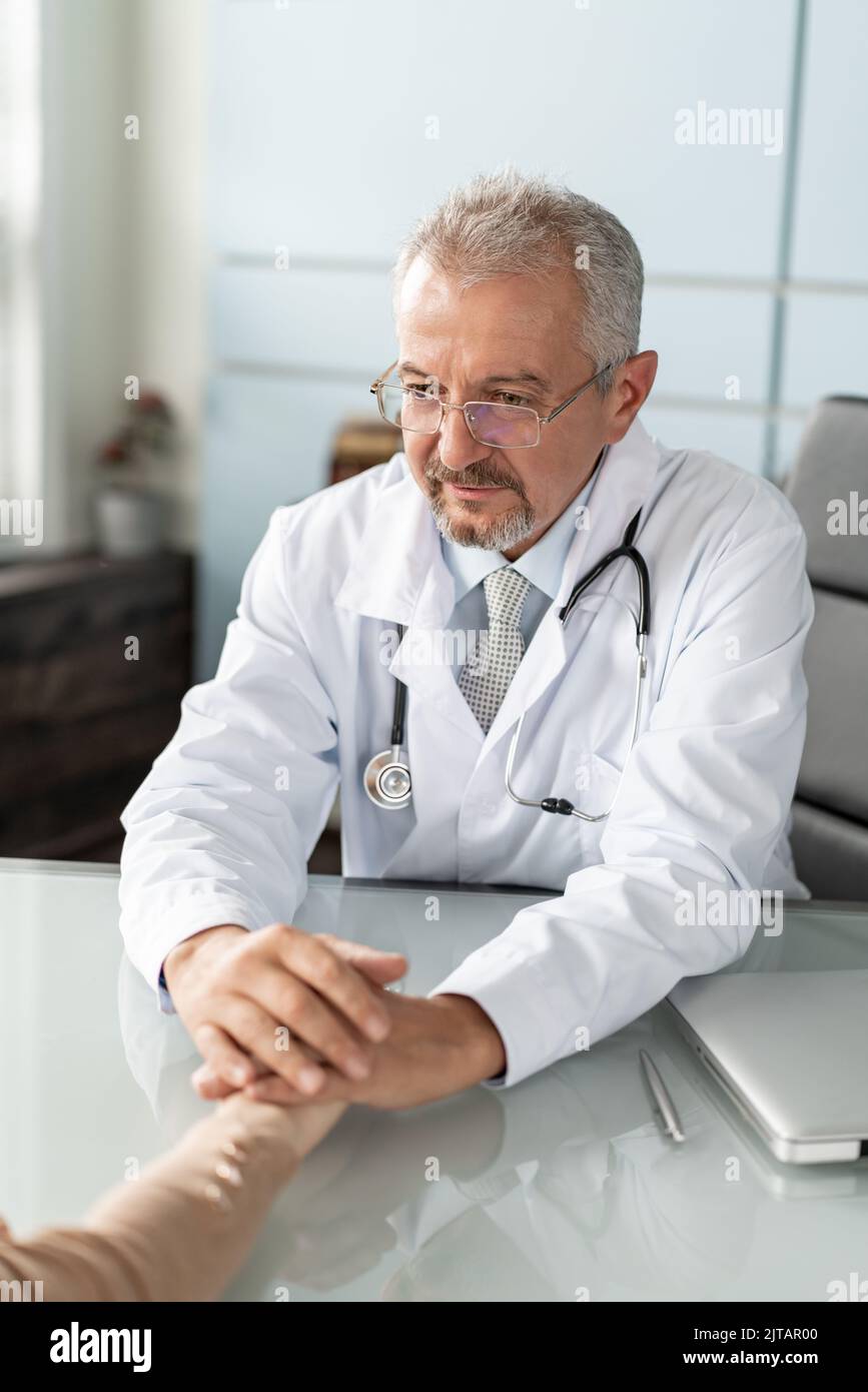 Doctor and patient are discussing something, just hands at the table. Stock Photo