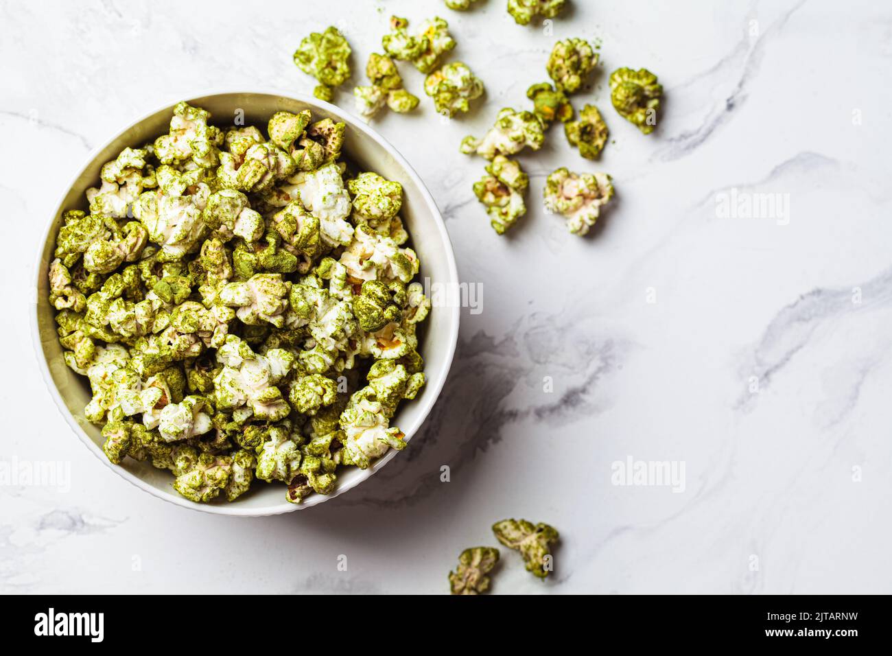 Vegan green spirulina popcorn in a white bowl, top view. Alternative
