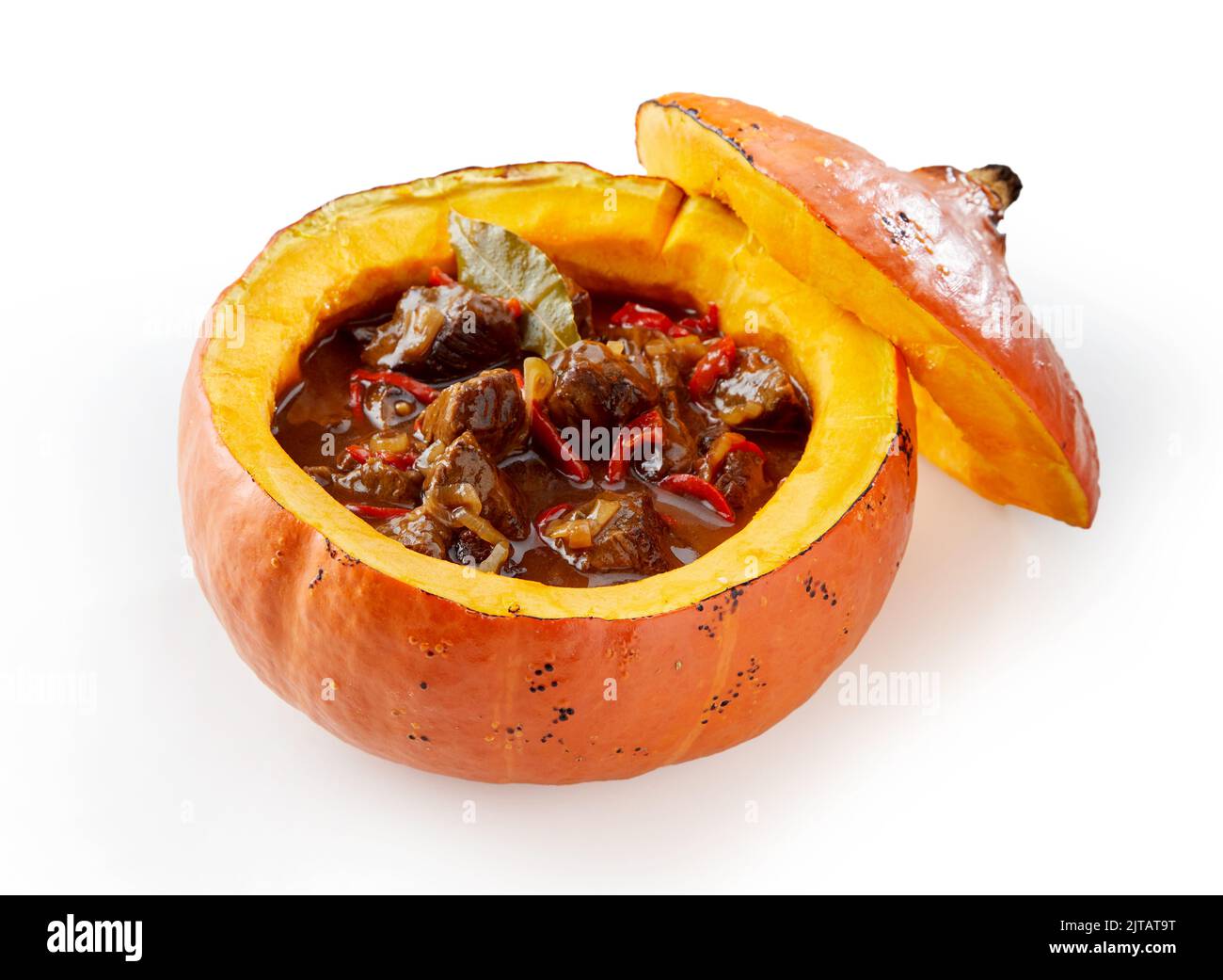 High angle of yummy meat goulash with vegetables and bay leaf served in small pumpkin on white background Stock Photo