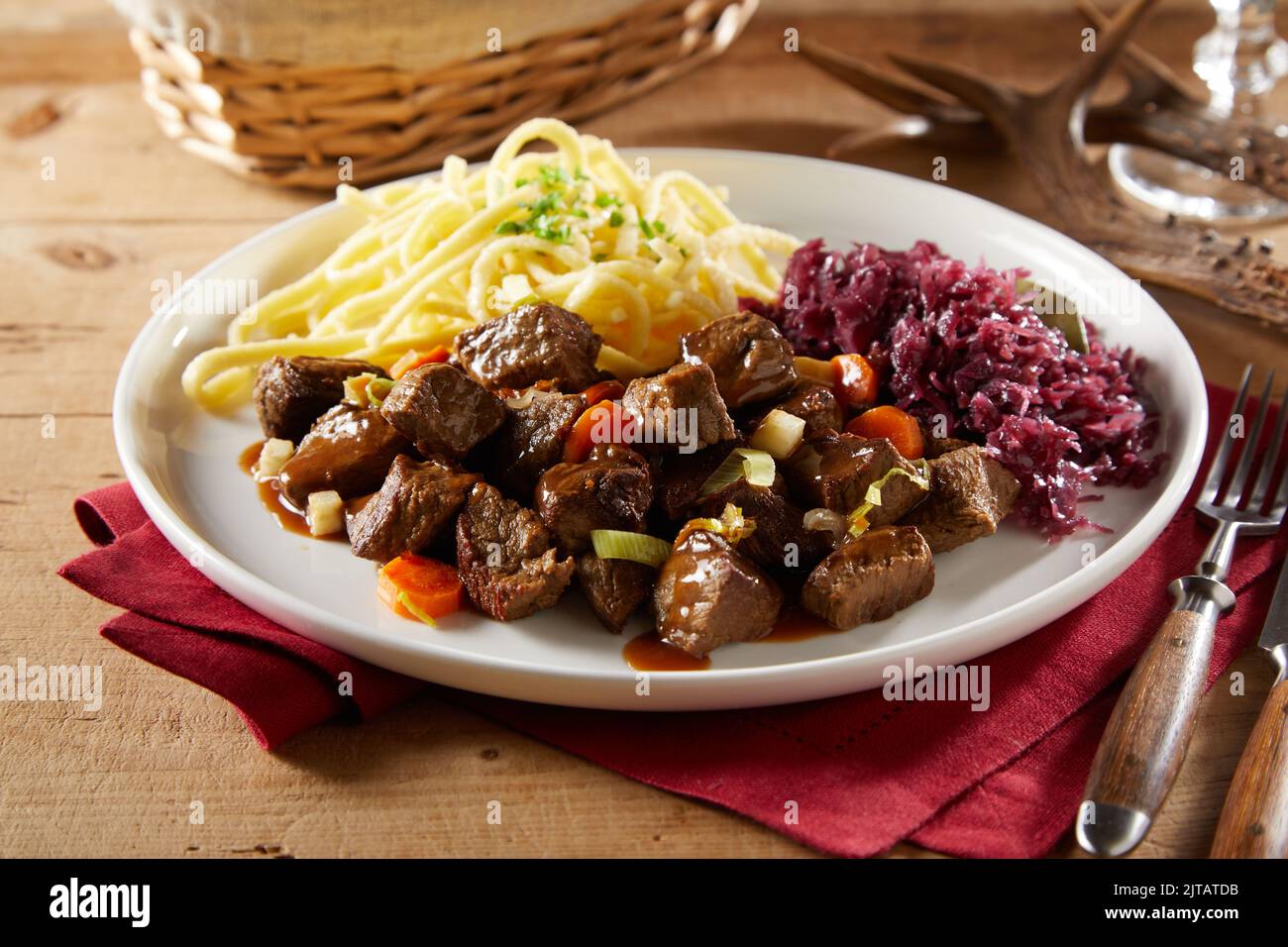 From above delicious beef goulash served on plate with spatzle pasta and red cabbage sauerkraut during lunch Stock Photo