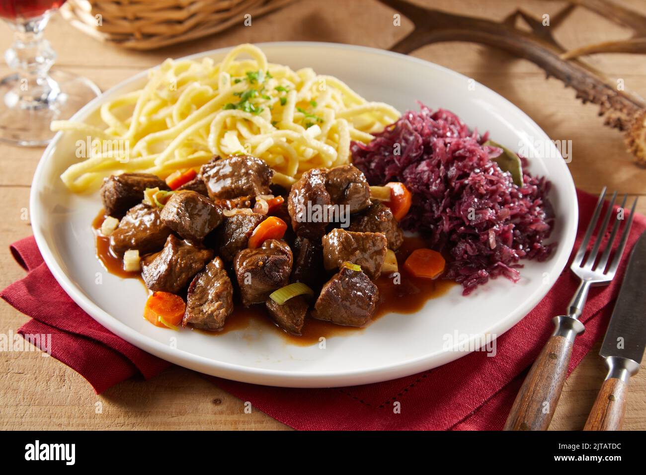From above meat goulash with spatzle pasta and sauerkraut served on plate near fork and knife during lunch Stock Photo
