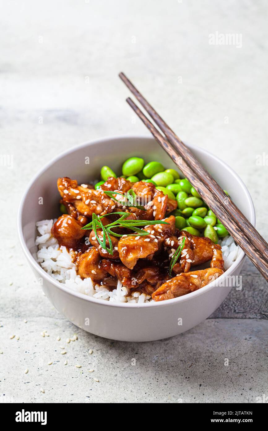 Teriyaki chicken with rice , onion and edamame beans in a gray bowl