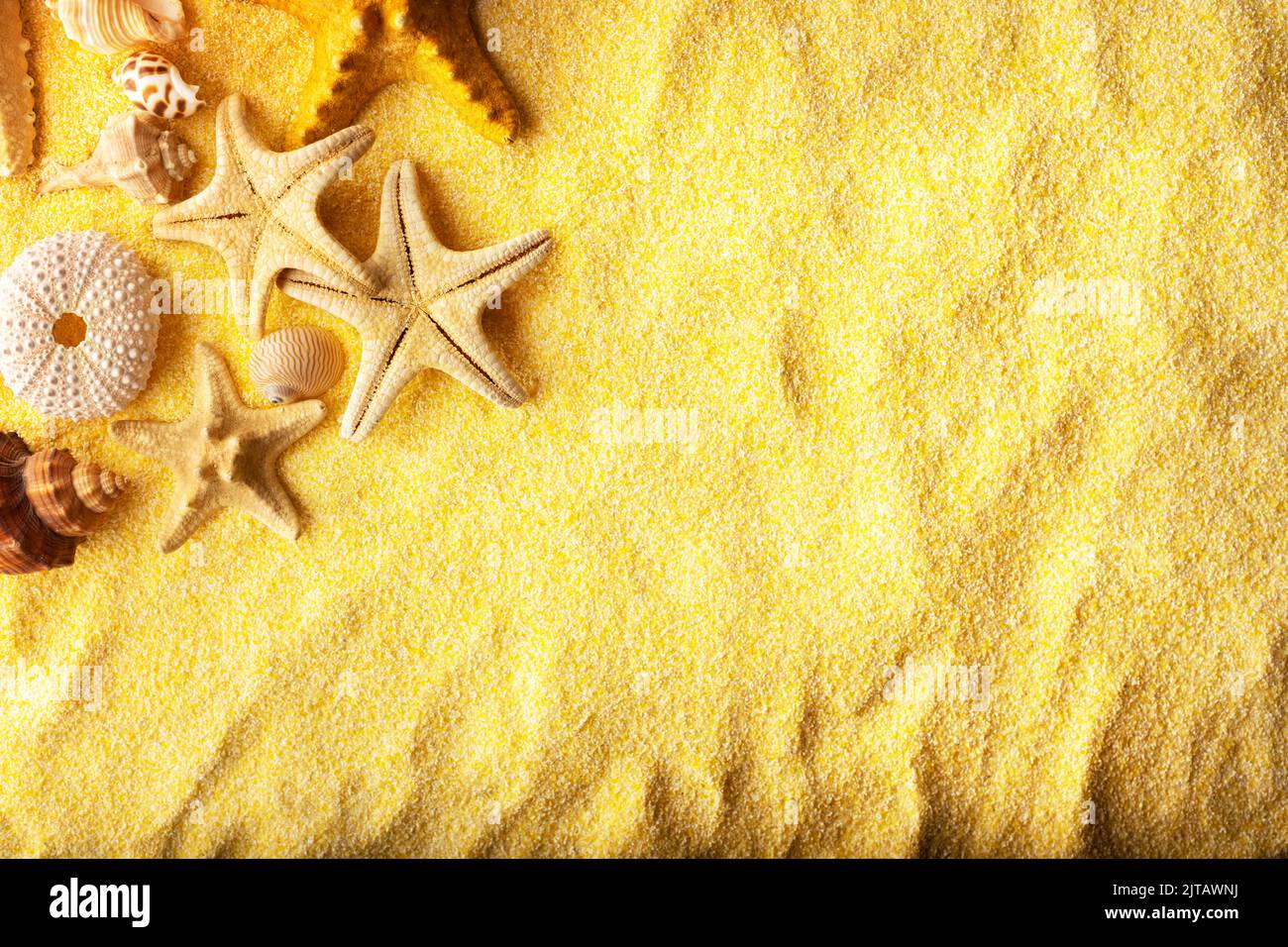 Vacations and summer time concept with starfish and sea shells on a clear yellow beach sand. Sea and ocean vacation background Stock Photo