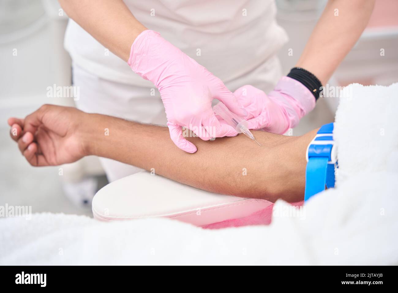 Nurse in nitrile gloves conducting venipuncture procedure Stock Photo