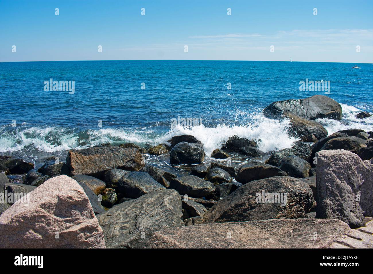 Waves crashing into rocky shoreline in Westerly, Rhode Island, on a sunny day with blue skies -05 Stock Photo
