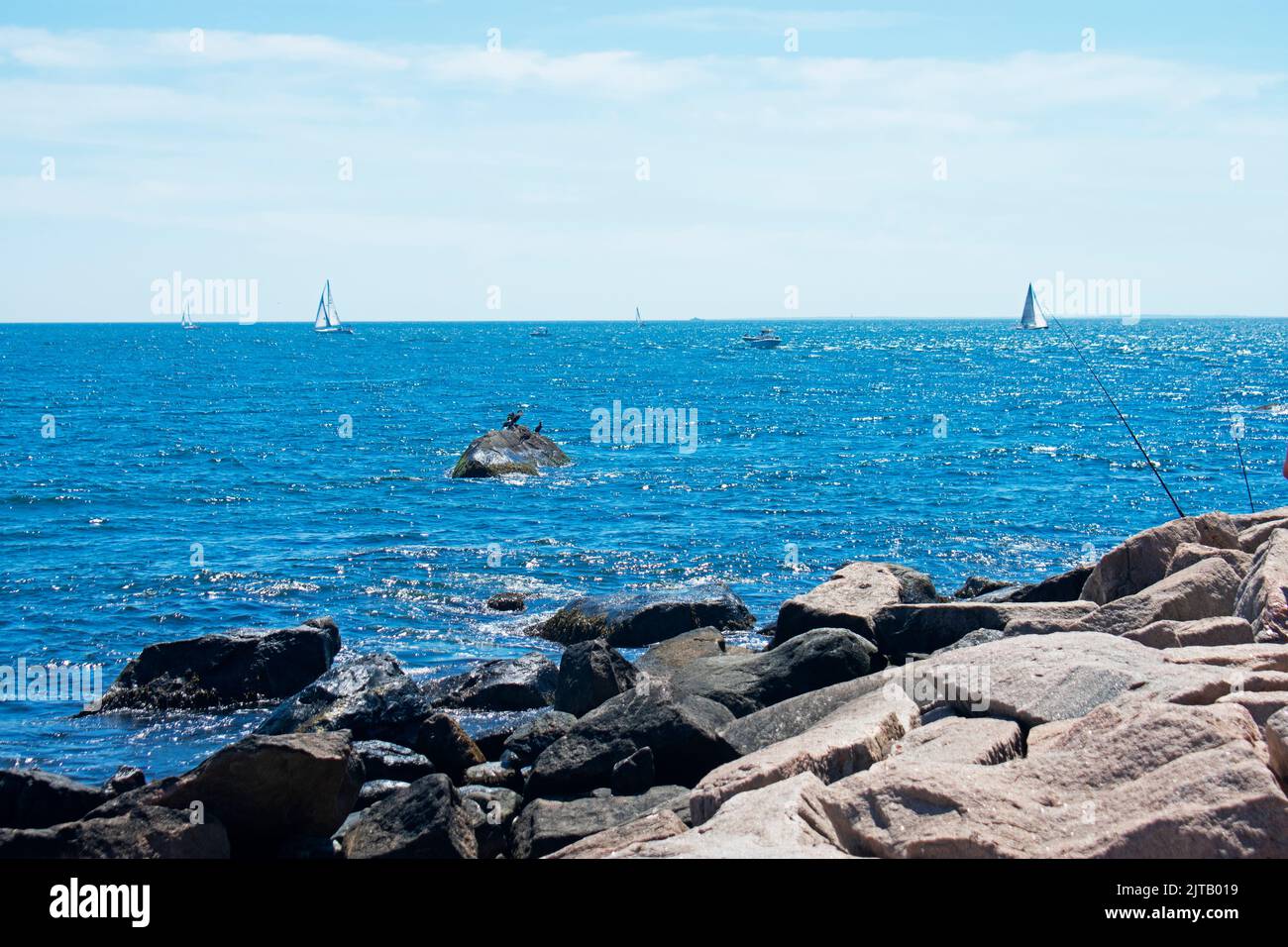 Fishing and sailing off the rocky shoreline in Westerly, Rhode Island, on a sunny day with blue skies -07 Stock Photo