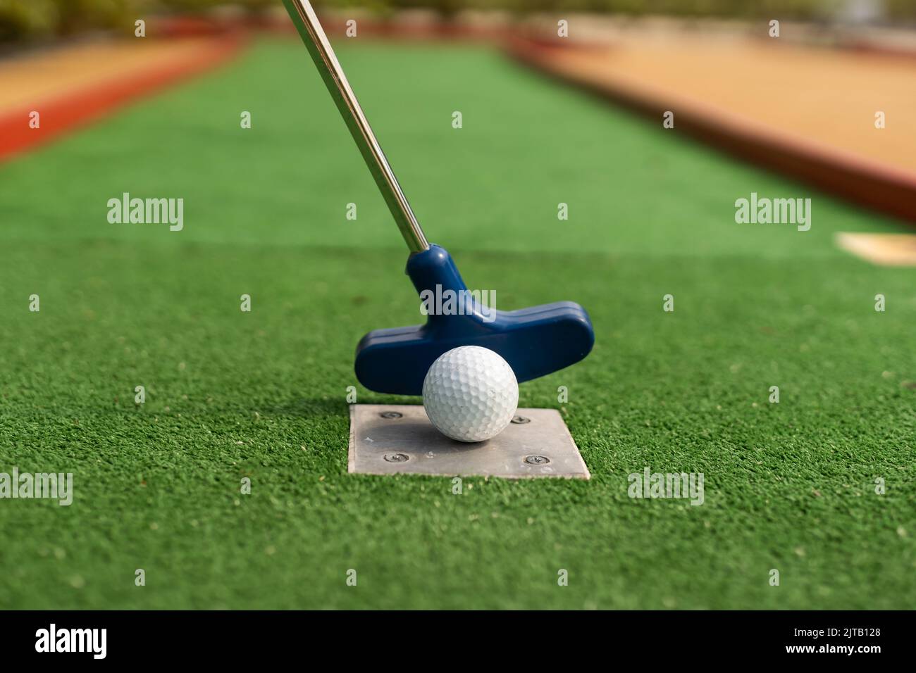 A club prepares to hit a ball during a mini golf game Stock Photo Alamy