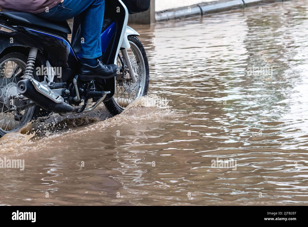 Man ride motorcycle passing through flooded road. Riding motorbike on