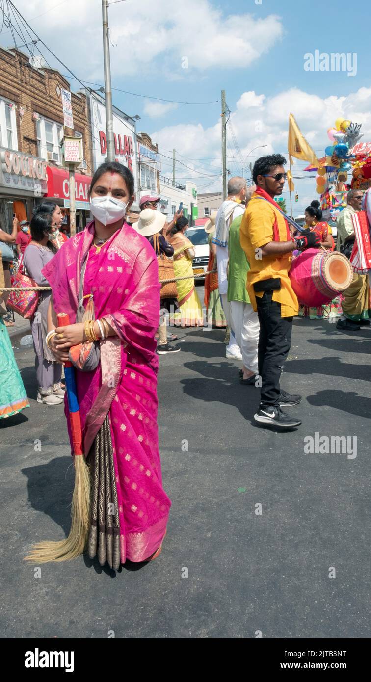 Posed portrait of a woman & broom. She swept the path of a chariot in the 2022 Queens, Rathayatra parade on Liberty Ave. in Richmond Hill, Queens, NYC Stock Photo