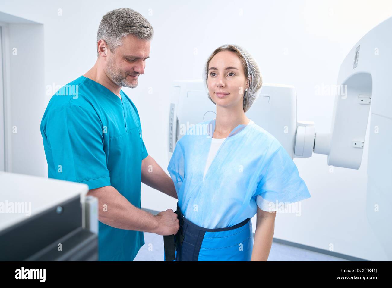 Radiologist putting lead shield on female patient Stock Photo