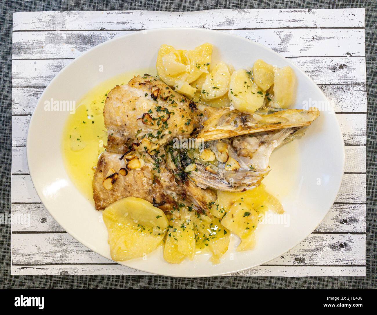Hake nape cut on the grill, seasoned with parsley oil and garlic. Basque country cuisine. Stock Photo