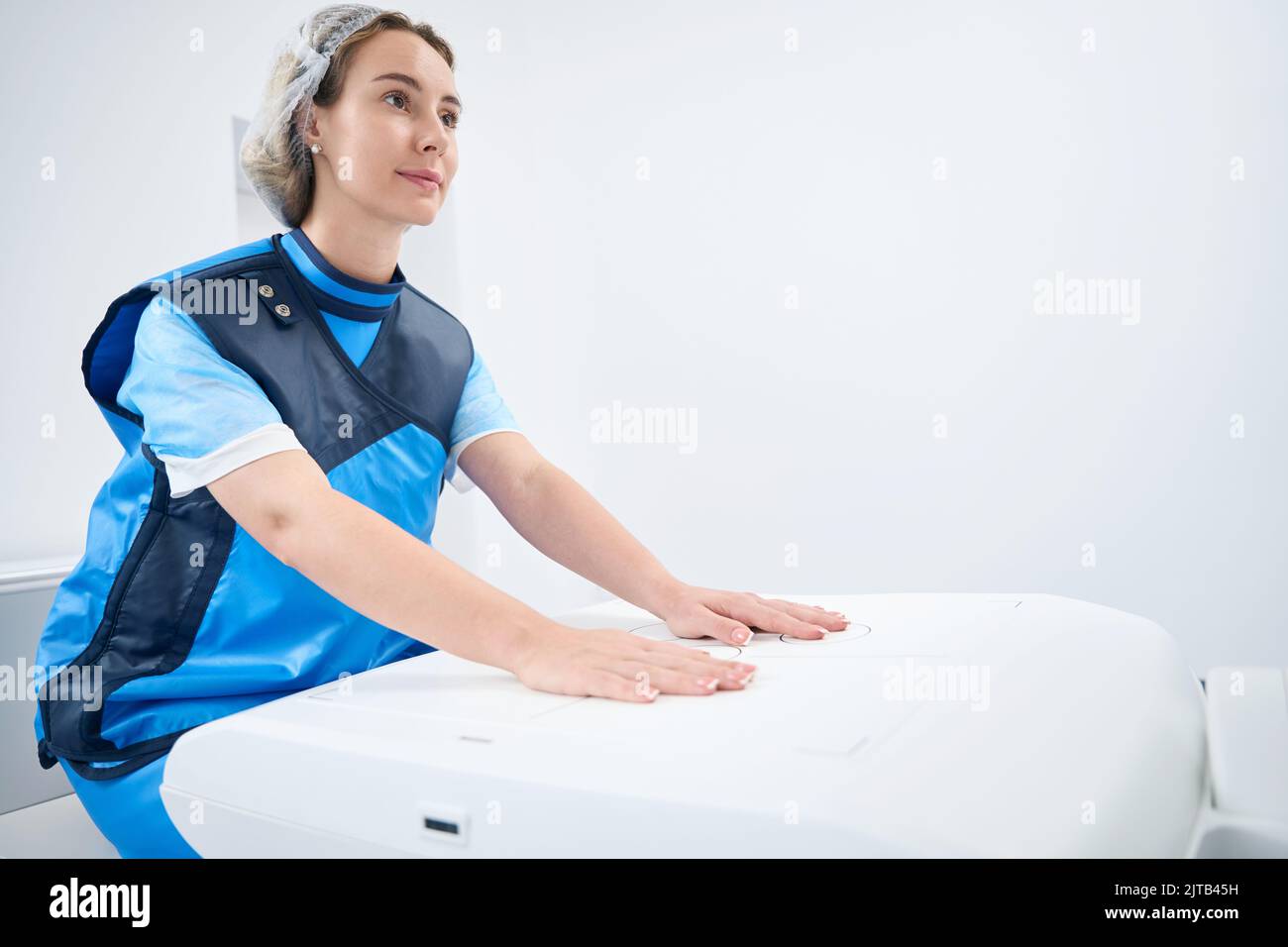 Woman in lead shield keeps her hands on the machine Stock Photo