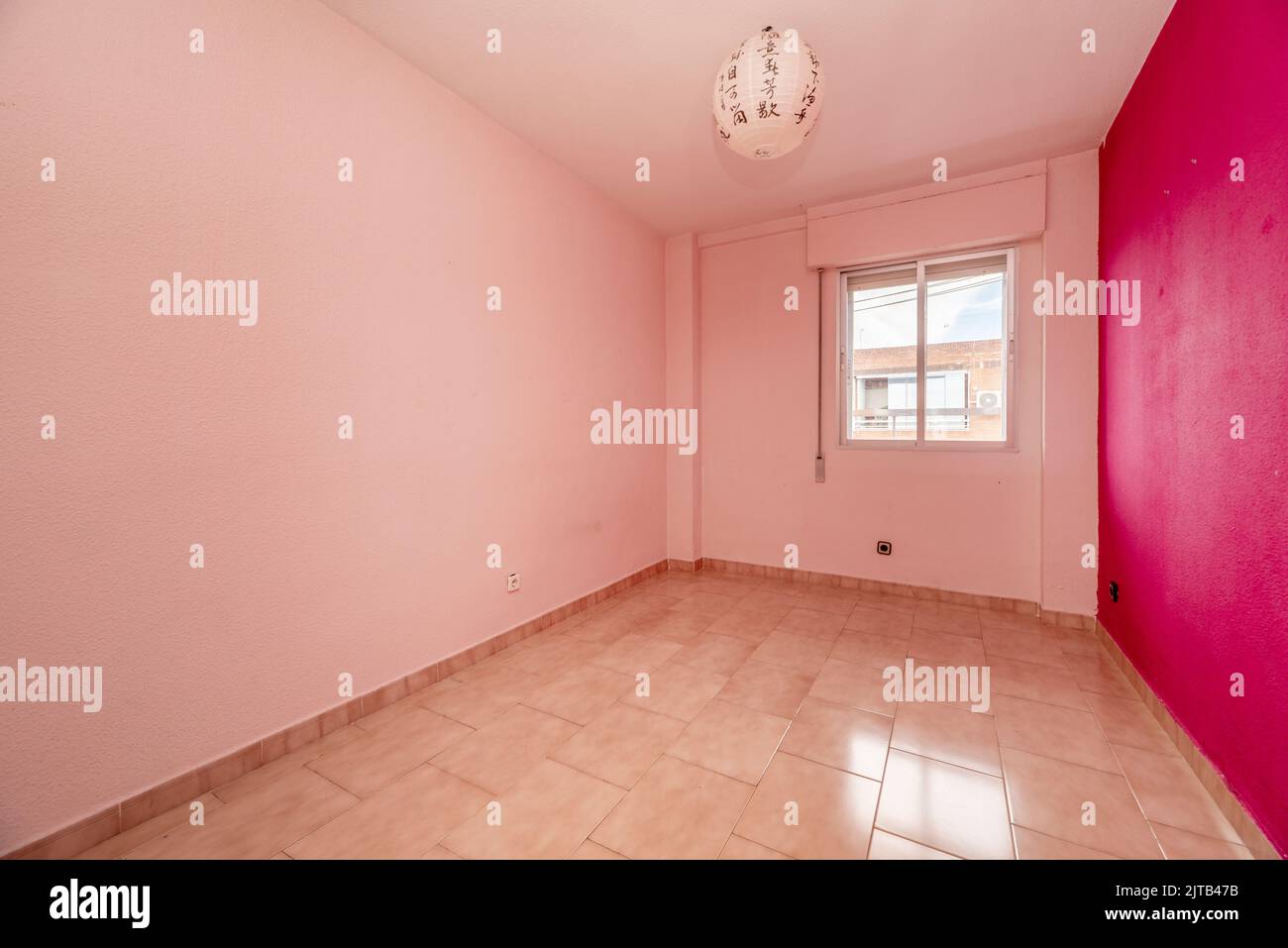 Empty living room in a residential house with stoneware floors and walls painted in various shades of pink Stock Photo
